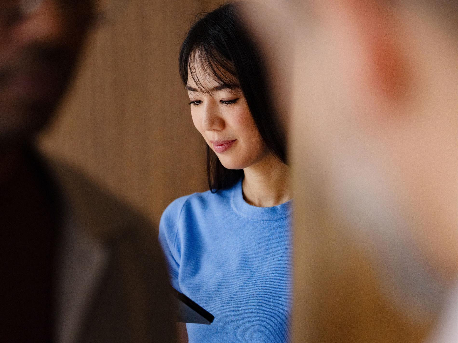 Woman in a blue top reads a tablet among colleagues