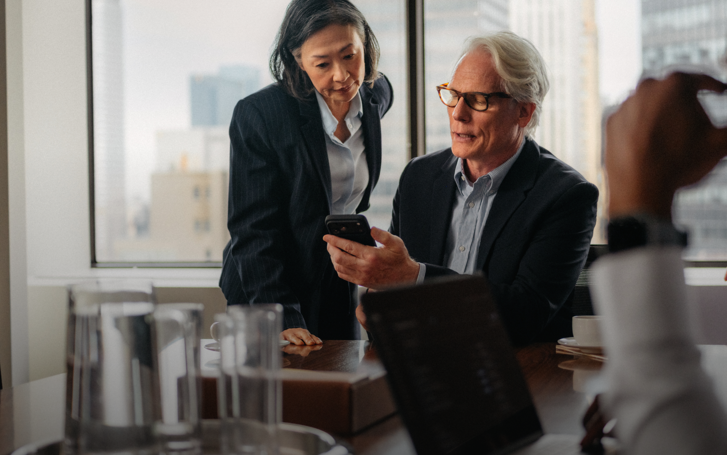 Two business colleagues looking at a smartphone in an office.