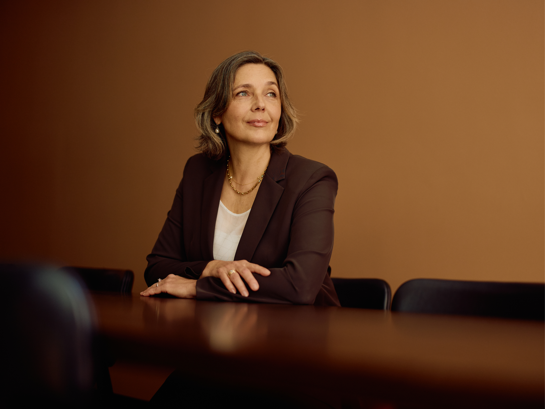 Woman in a dark blazer smiles at a boardroom table