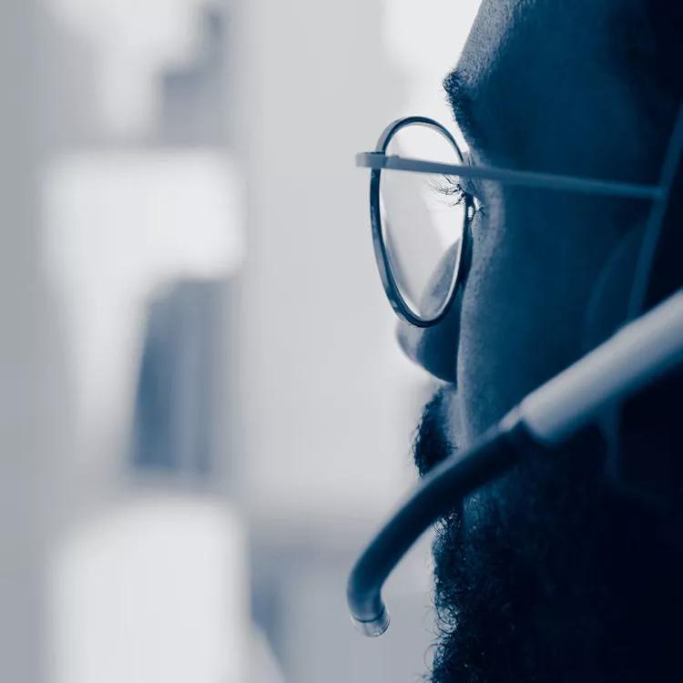 Close-up side profile of a person wearing glasses and a headset microphone.