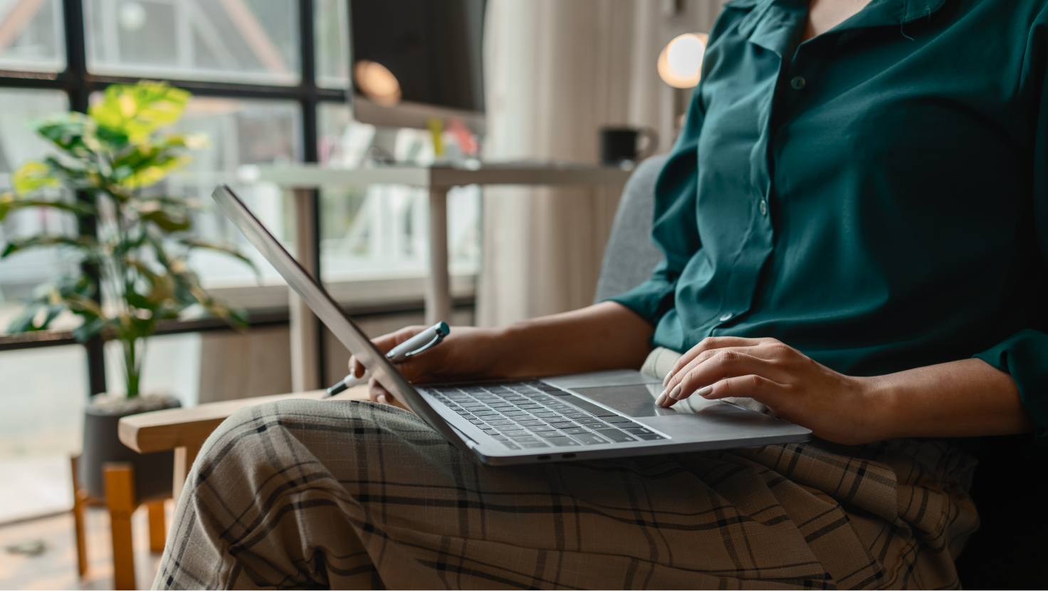 Person typing on a laptop while holding a pen.