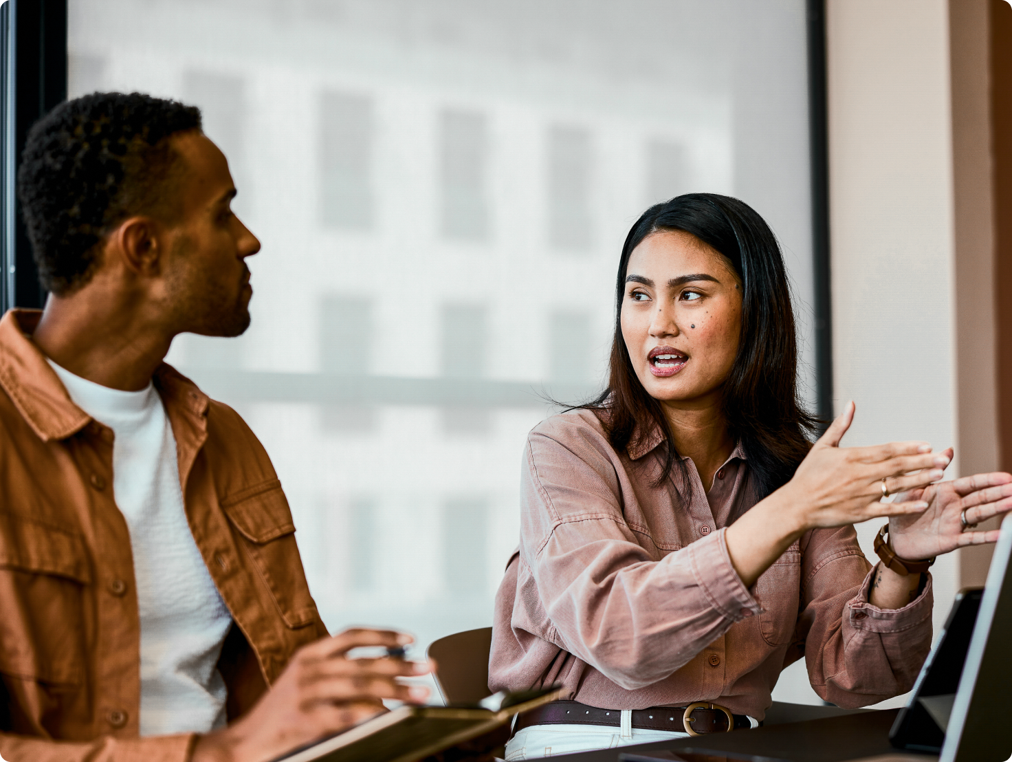 Woman speaking and gesturing to a man listening.