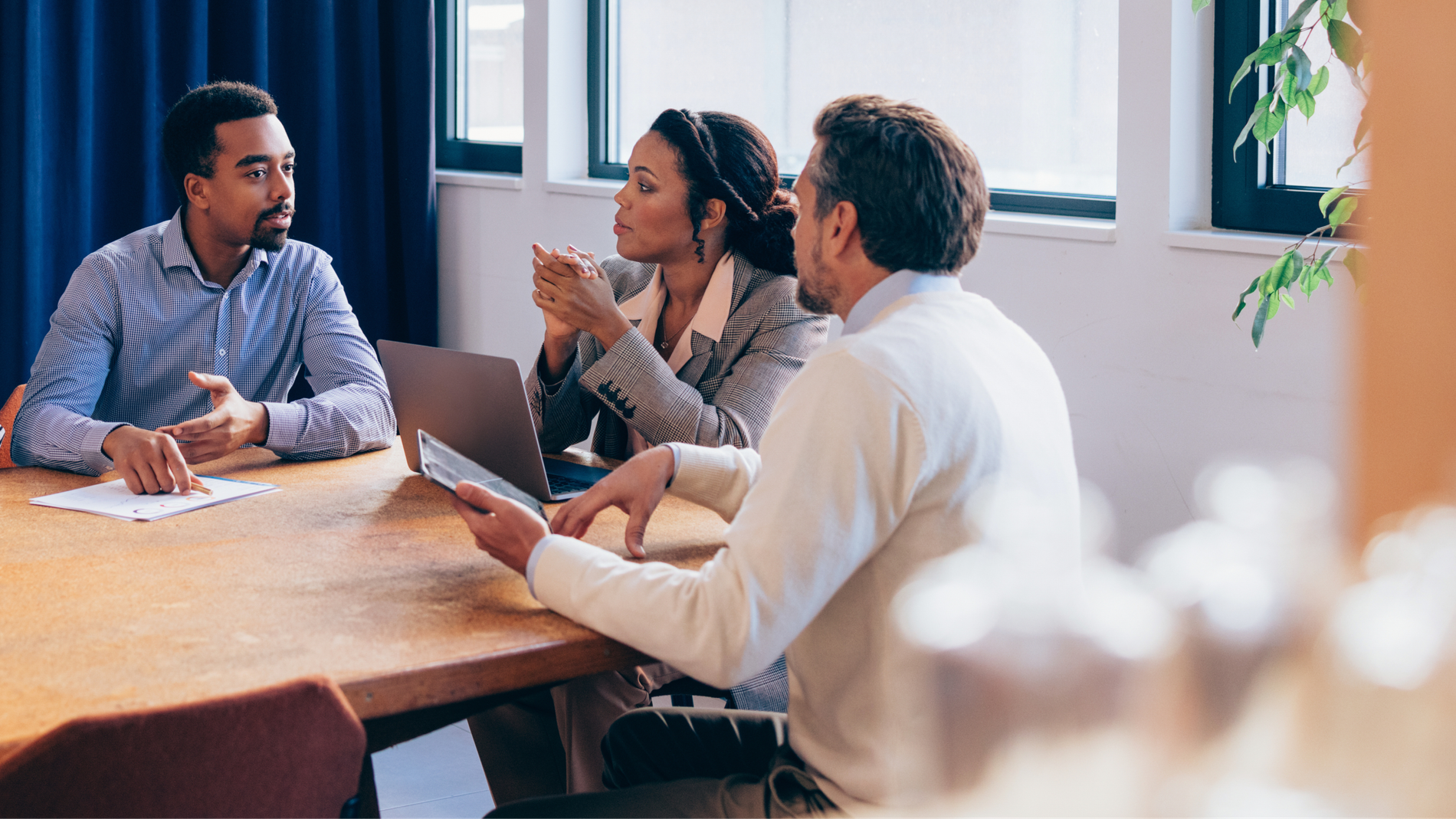 Three people discussing at a conference table.