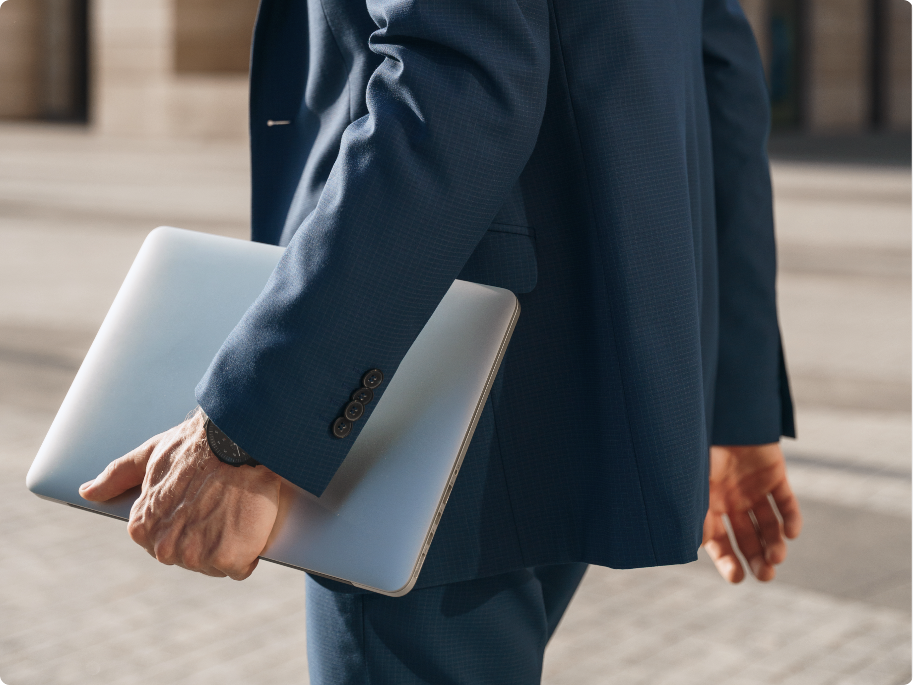 Person in a blue suit holding a silver laptop.
