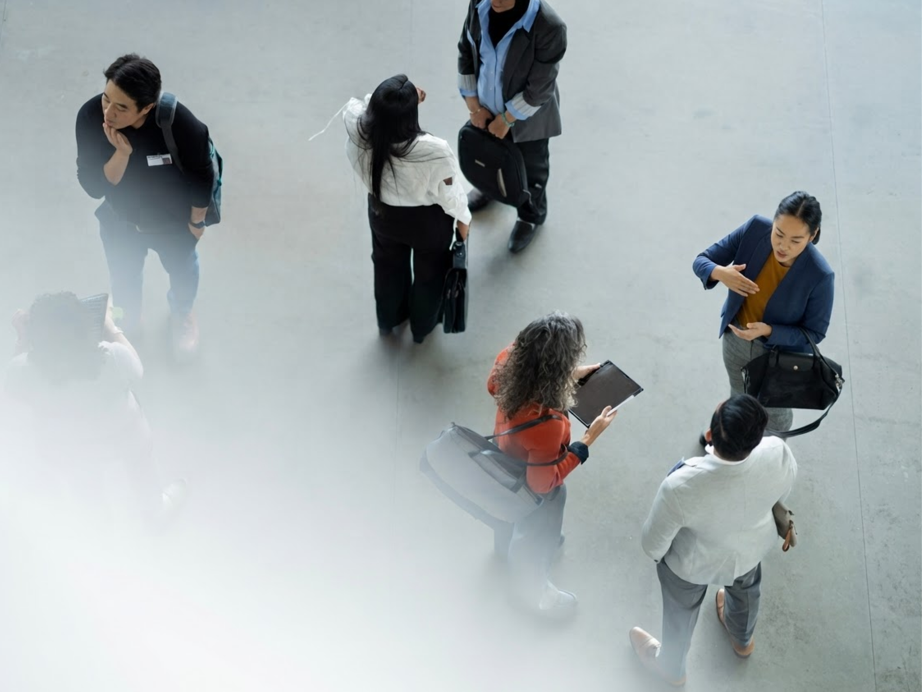 Overhead view of professionals talking in small groups in a bright atrium