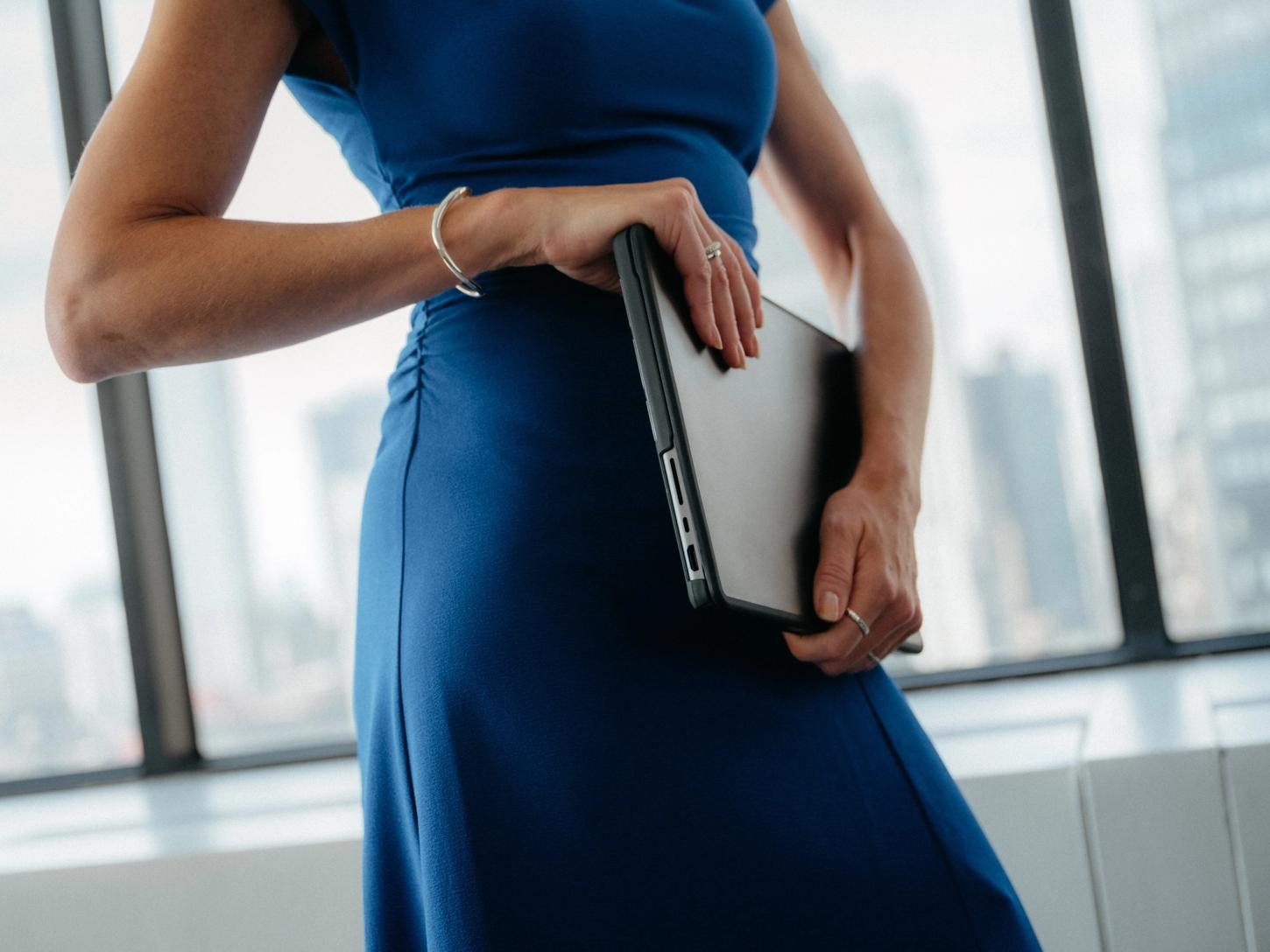 A lawyer holding a laptop by an office window