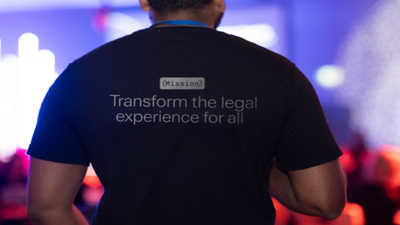 Back of a person wearing a black t-shirt with the text "Mission: Transform the legal experience for all."