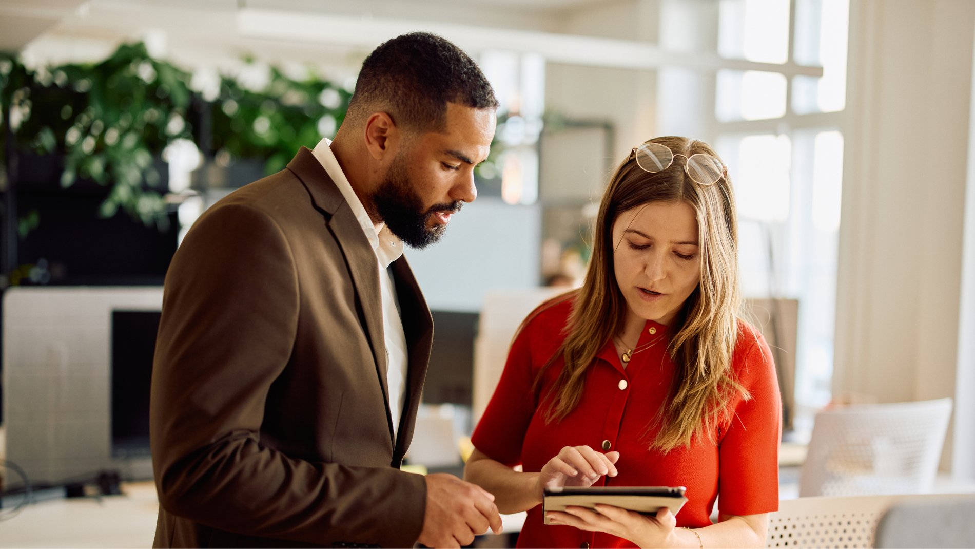 A woman shows a tablet to a man in an office.