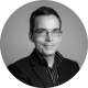 A black-and-white photo of a white man wearing glasses and a blazer and striped shirt. He is Peter Wright, Founder of Digital Law, and a guest author on the Clio UK blog