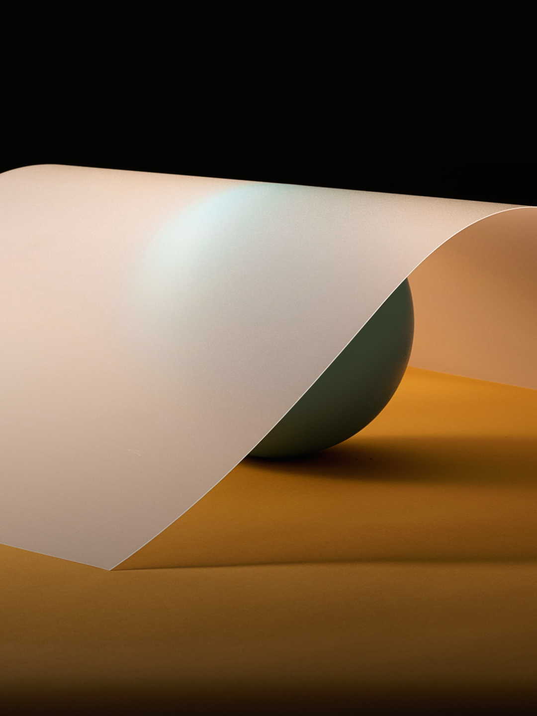 A translucent sheet curves over a green sphere on an orange surface with a black background.