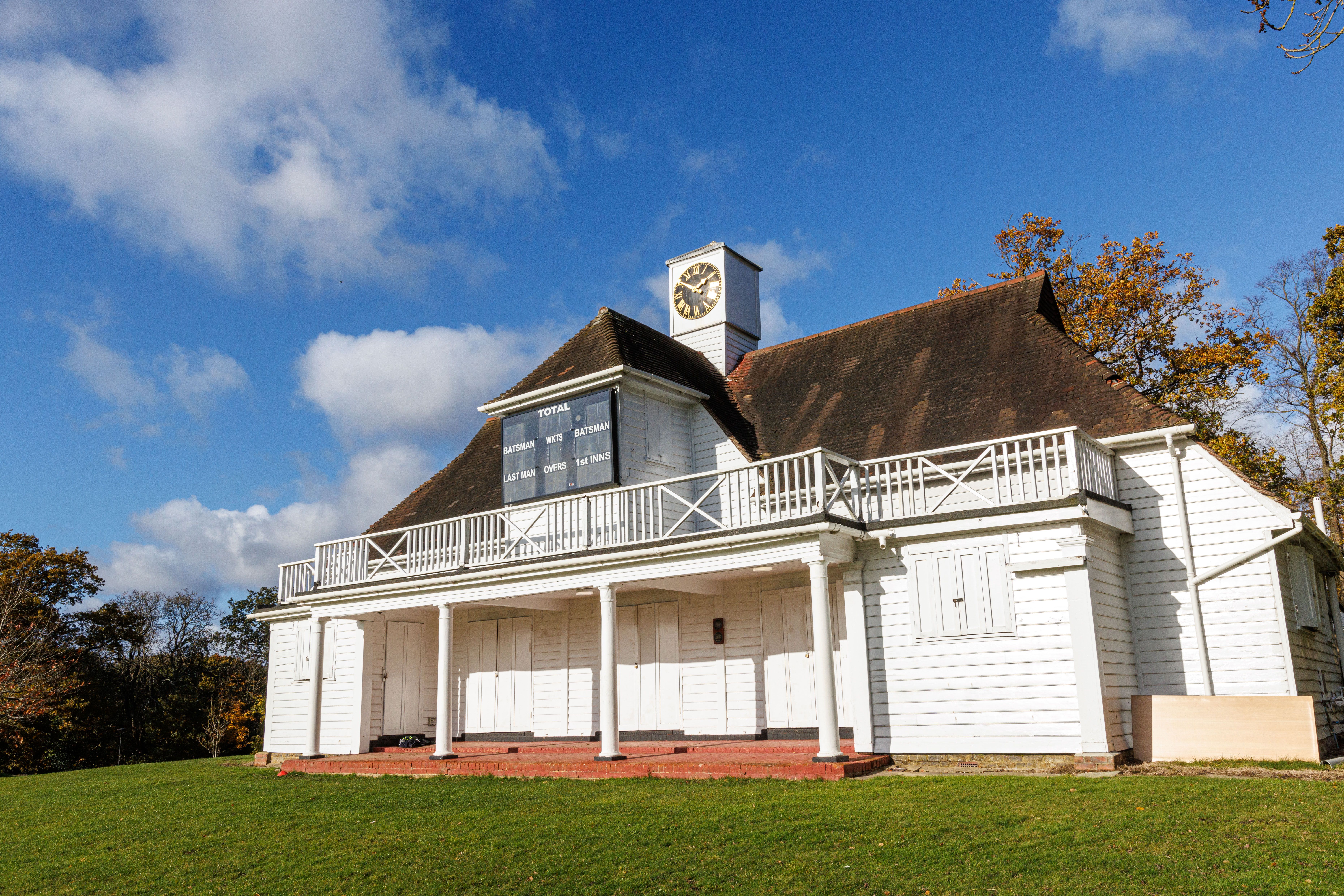 An image of a white building with a clock tower on top on a grassy hill 