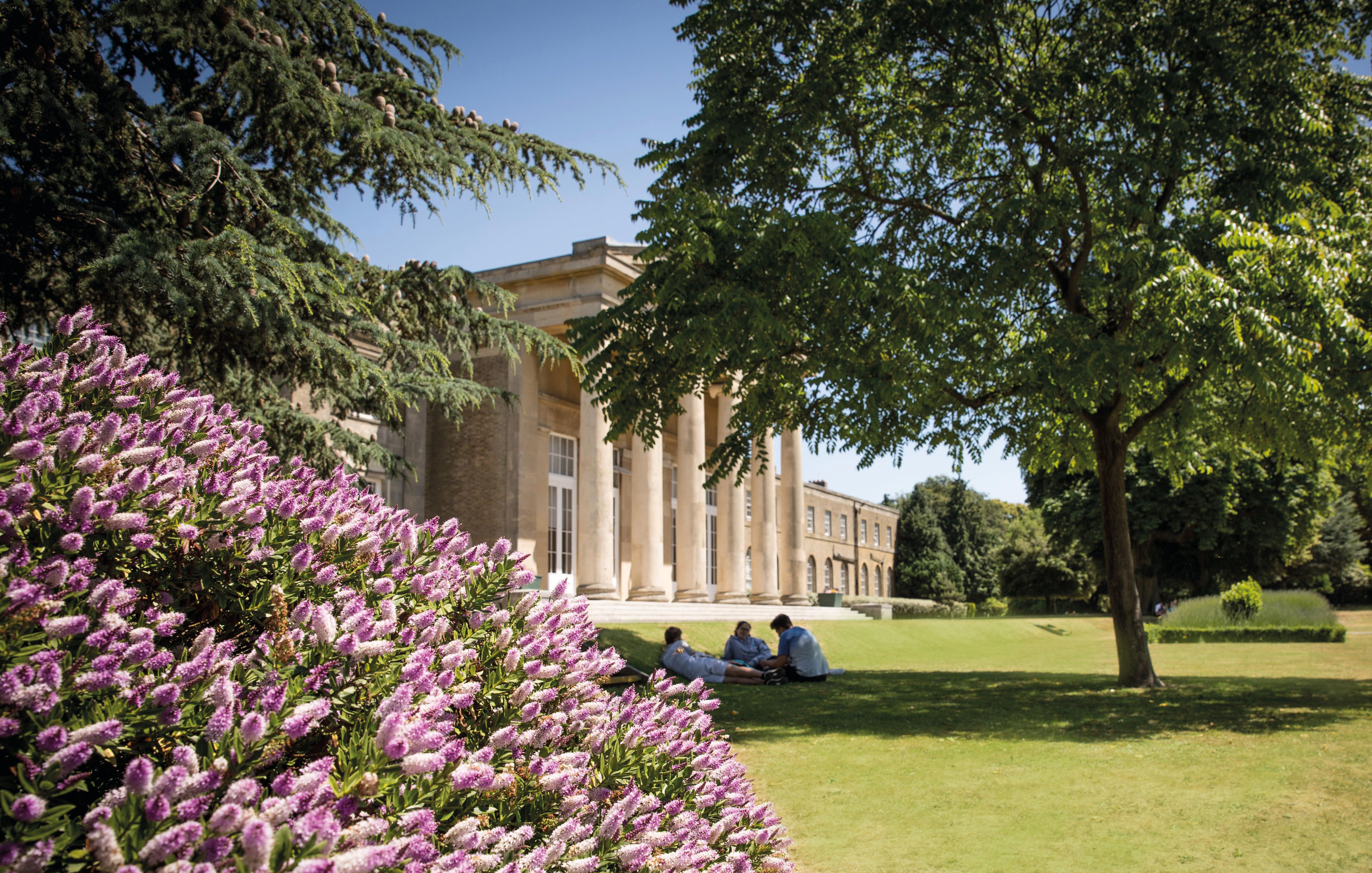 Image of Mill Hill school grounds with three people on the grass 
