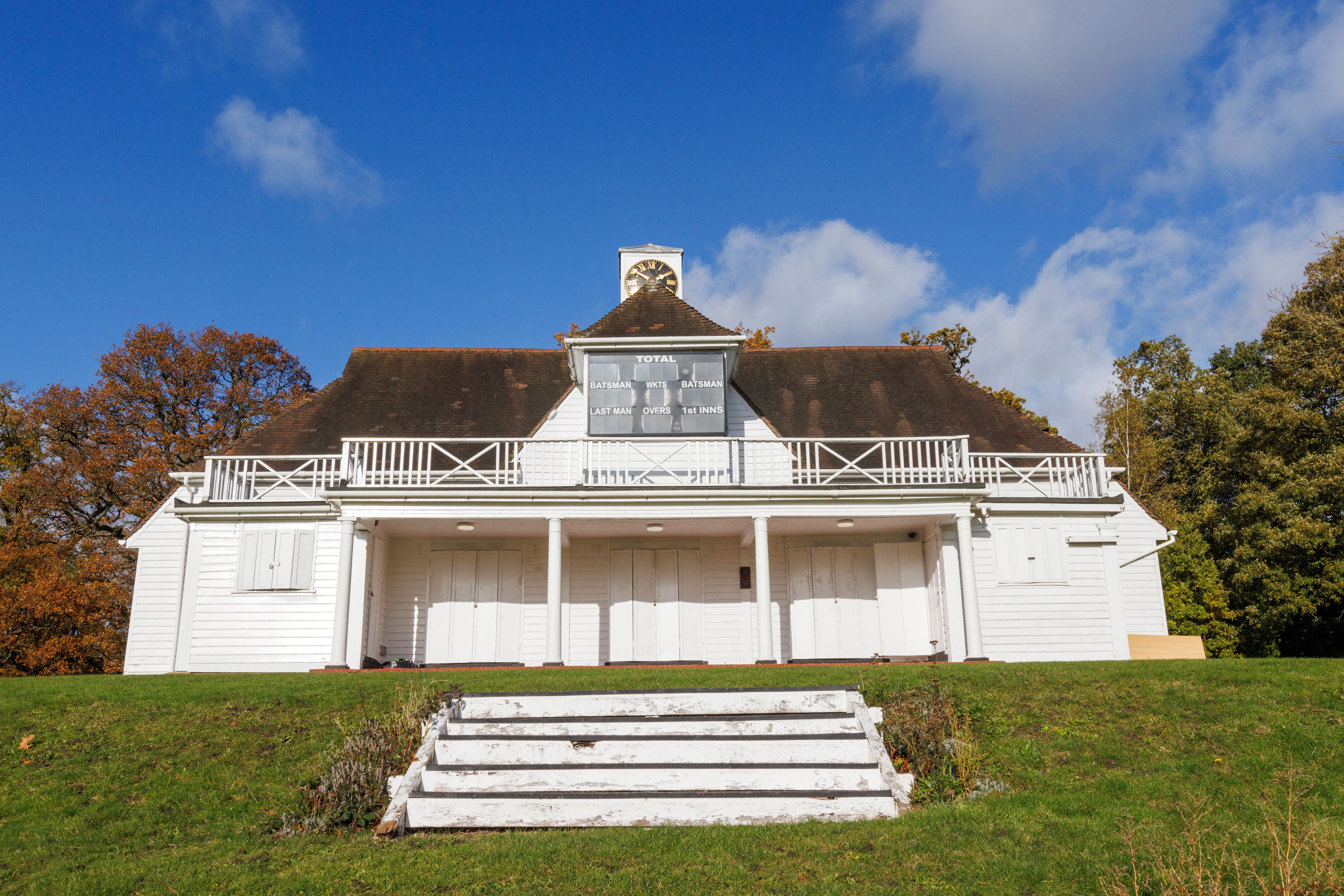 An image of a white building with a clock tower on top on a grassy hill 