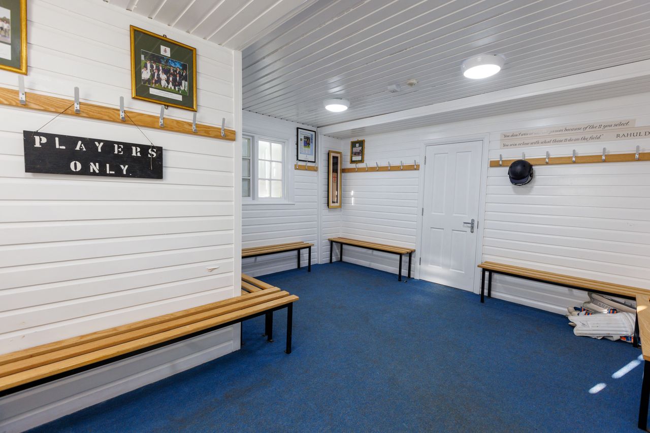 A changing room with blue carpeting and wooden benches and a sign that says "PLAYERS ONLY" 