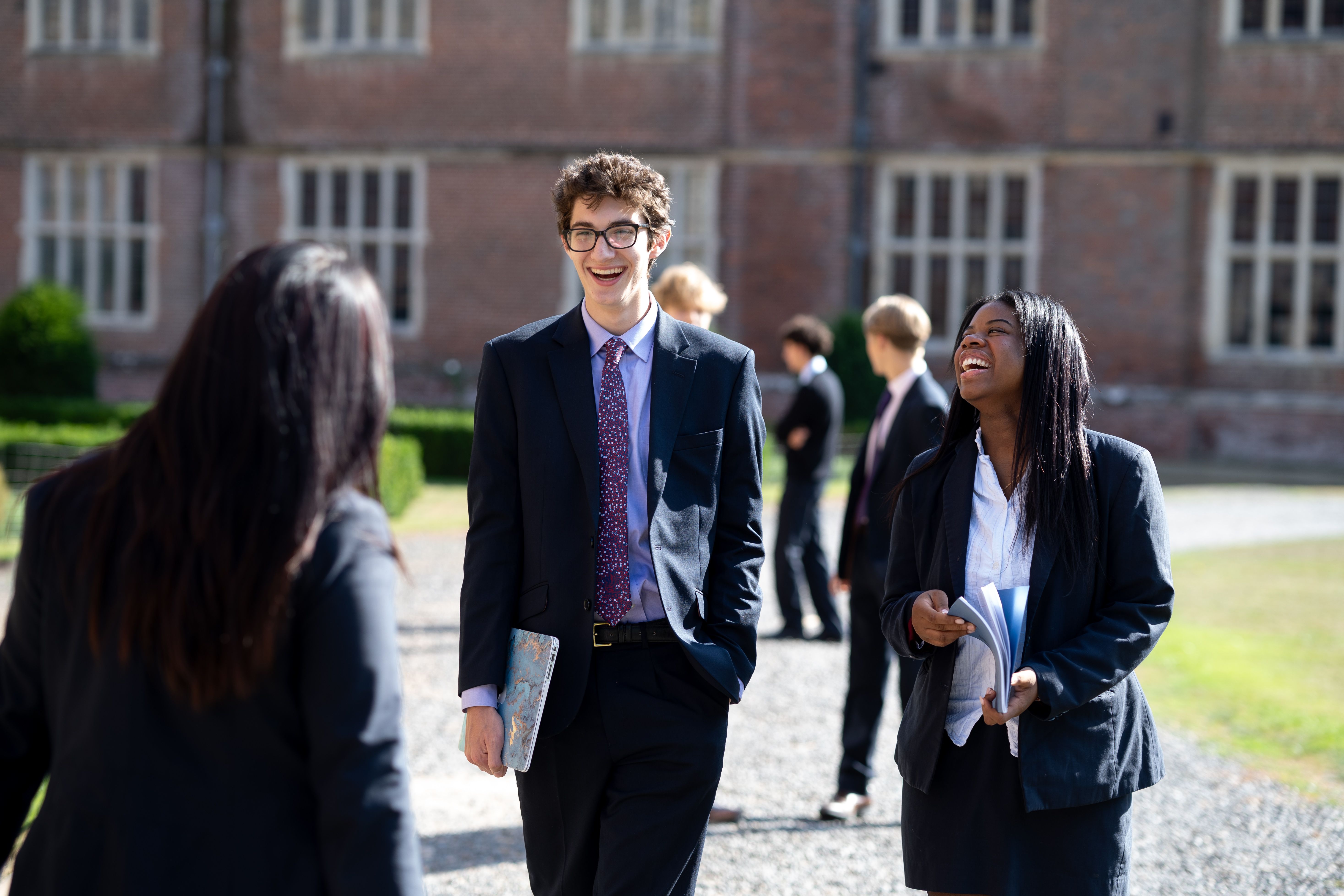 Two girls from Cobham Hall School sitting down and laughing outside 