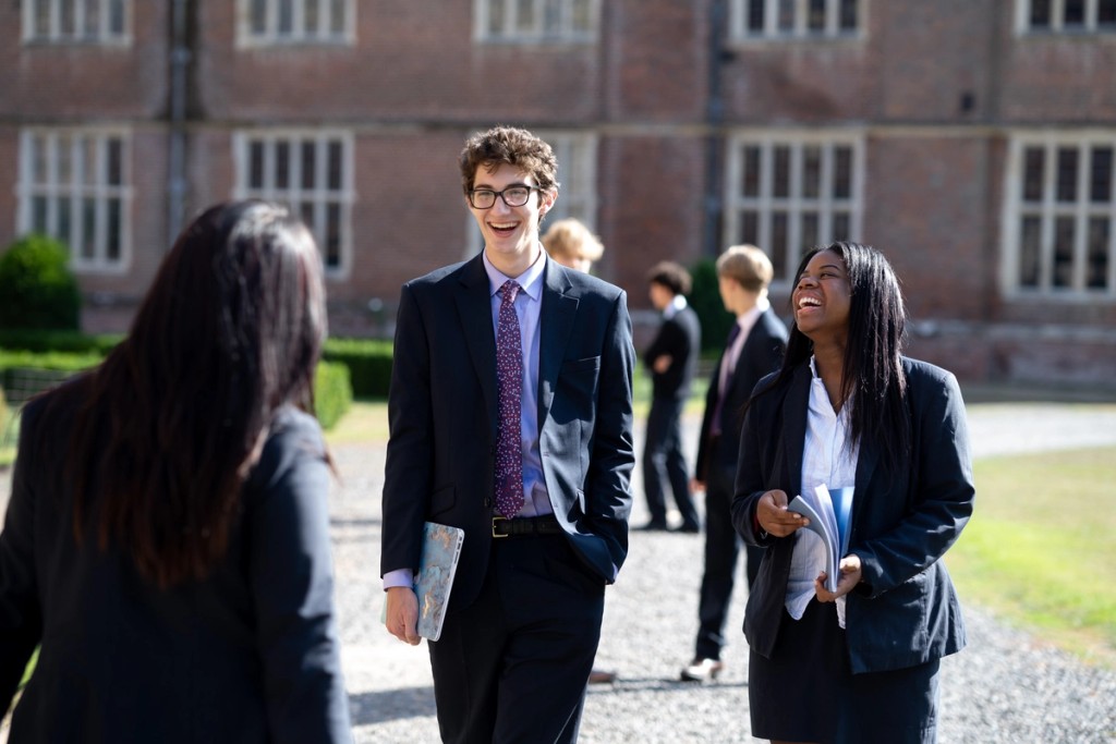 Two girls from Cobham Hall School sitting down and laughing outside 