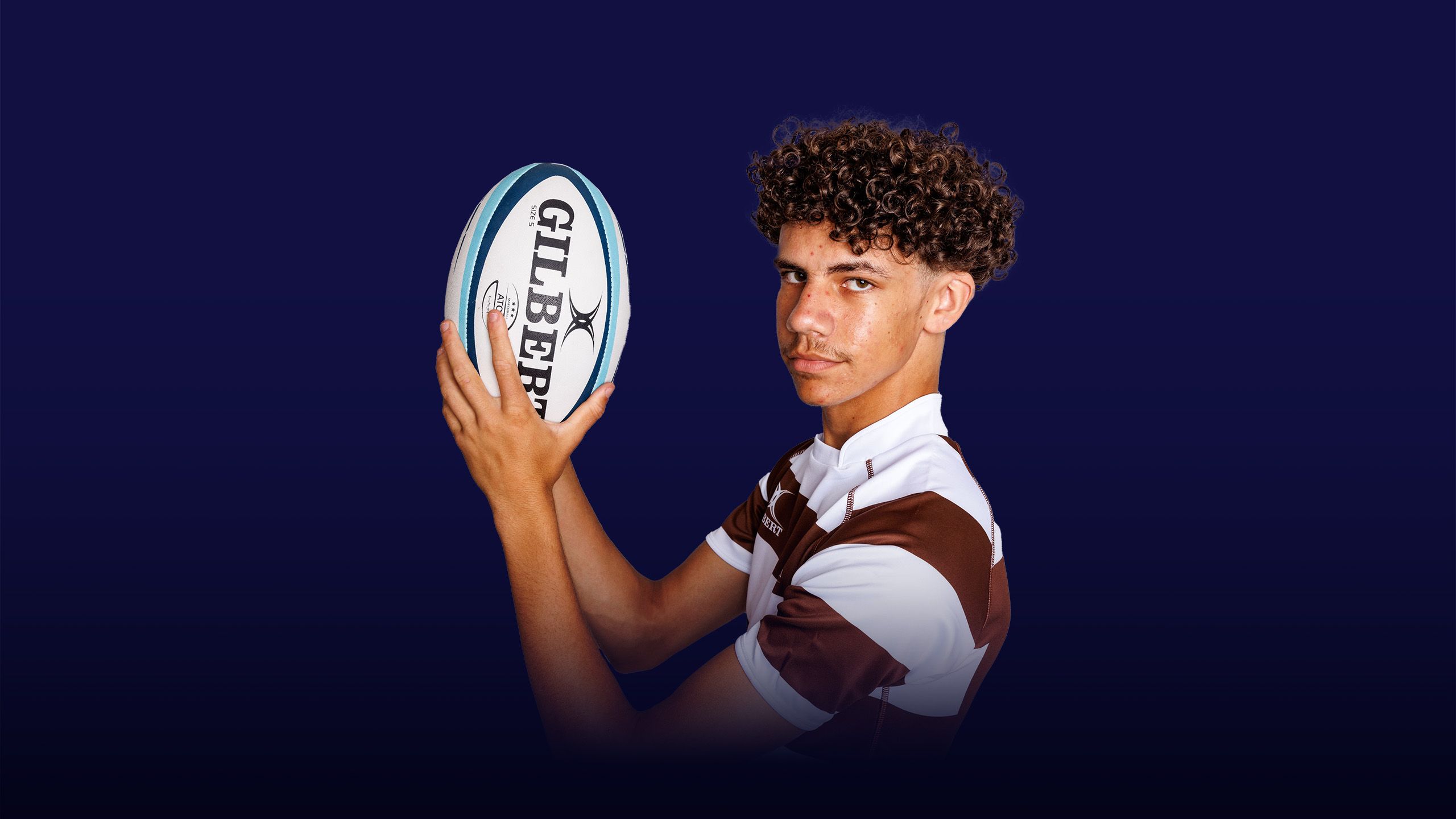 Image of a boy holding up a rugby ball with an overlay of the text "instilling values"