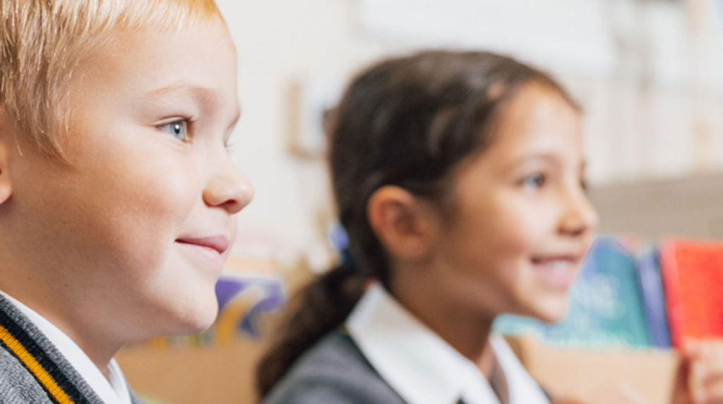A close up side view of two kids in a classroom 