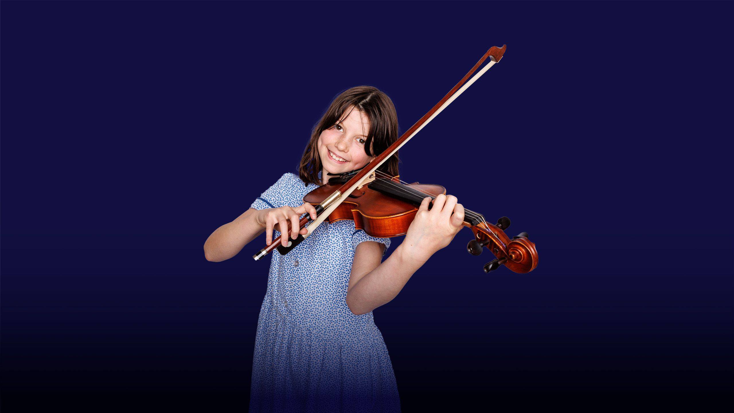 Image of a smiling girl at a violin playing position with an overlay of the text "inspiring minds" 