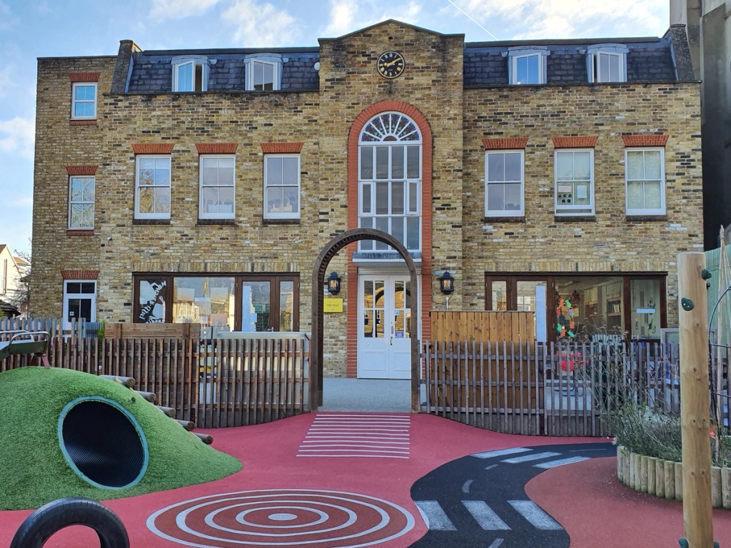 Image taken at Keble Prep School of a large brick building with a clock tower and a playground in front