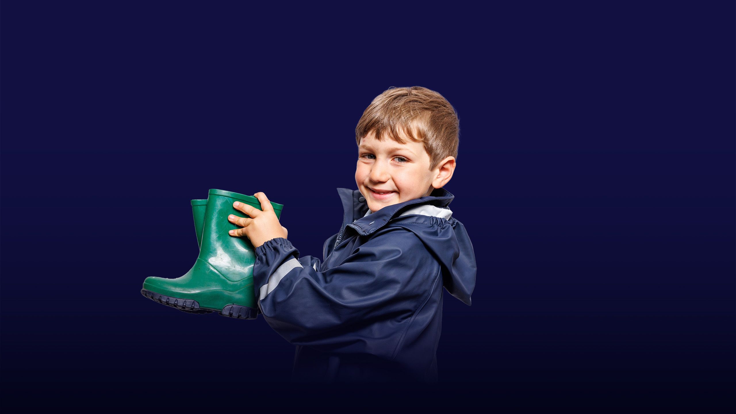 Image of a little boy holding green wellies with an overlay of the text "inspiring minds"