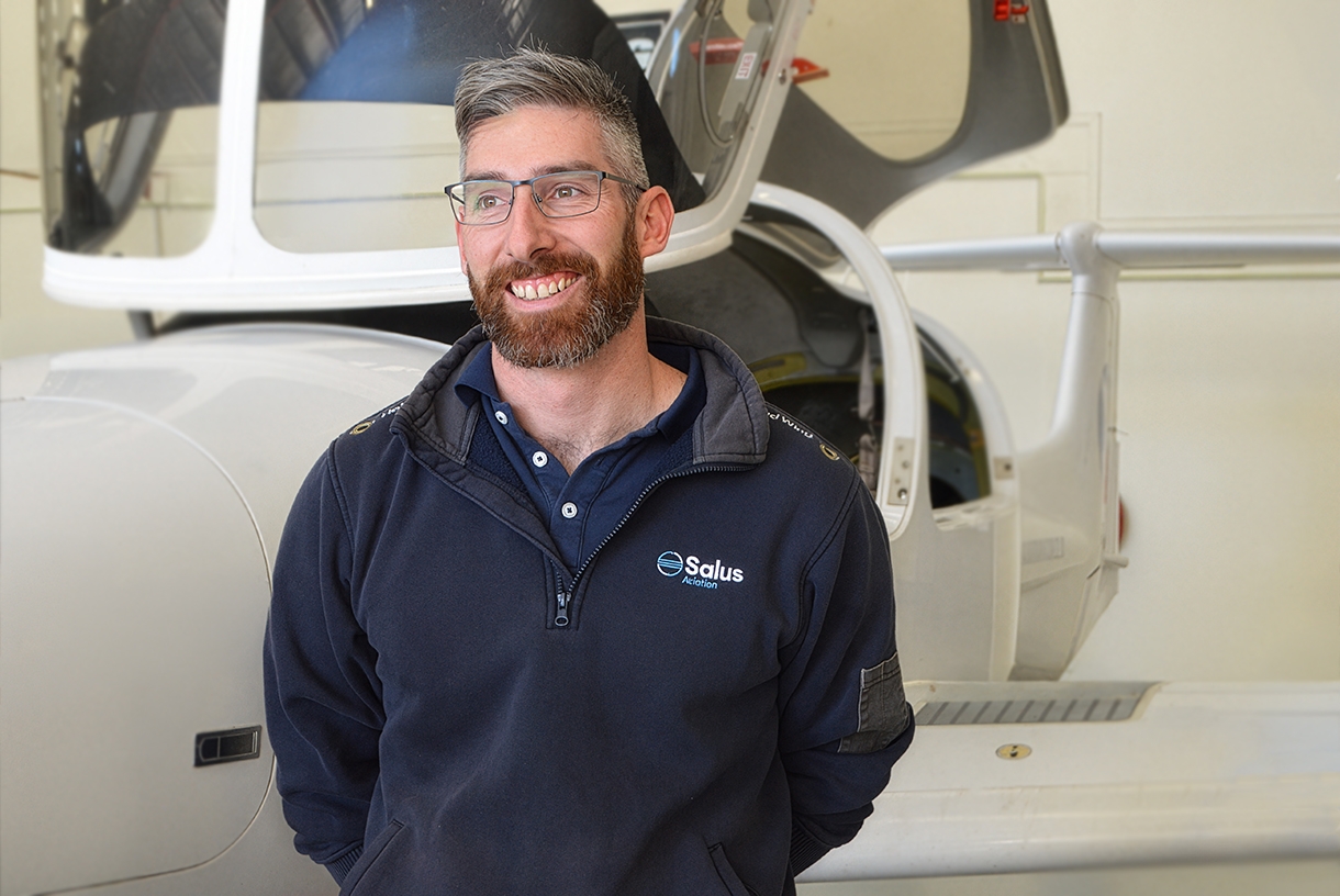 Carey Pyper beside a fixed wing aircraft in hangar