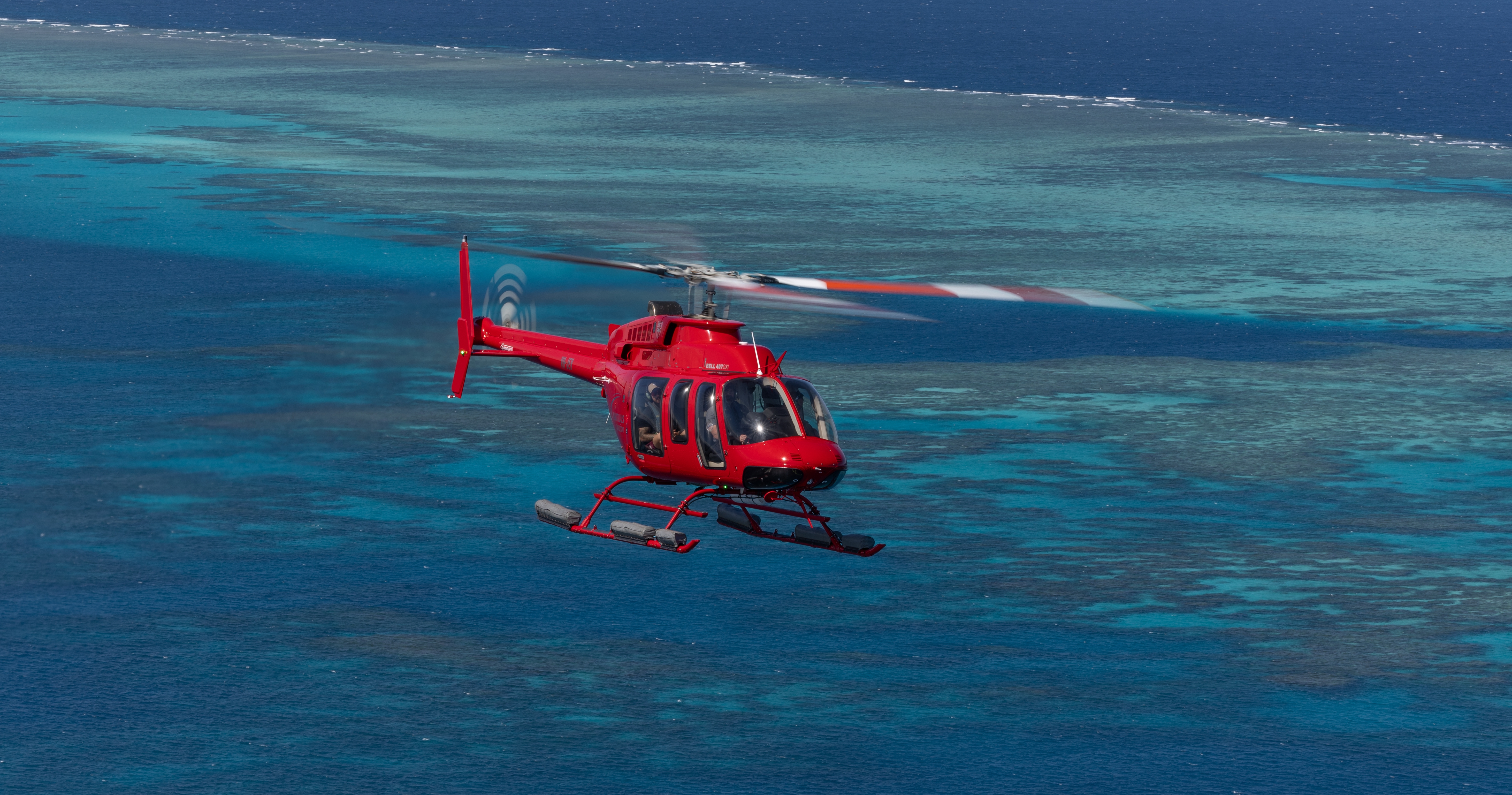 Bell 407 helicopter flying above ocean
