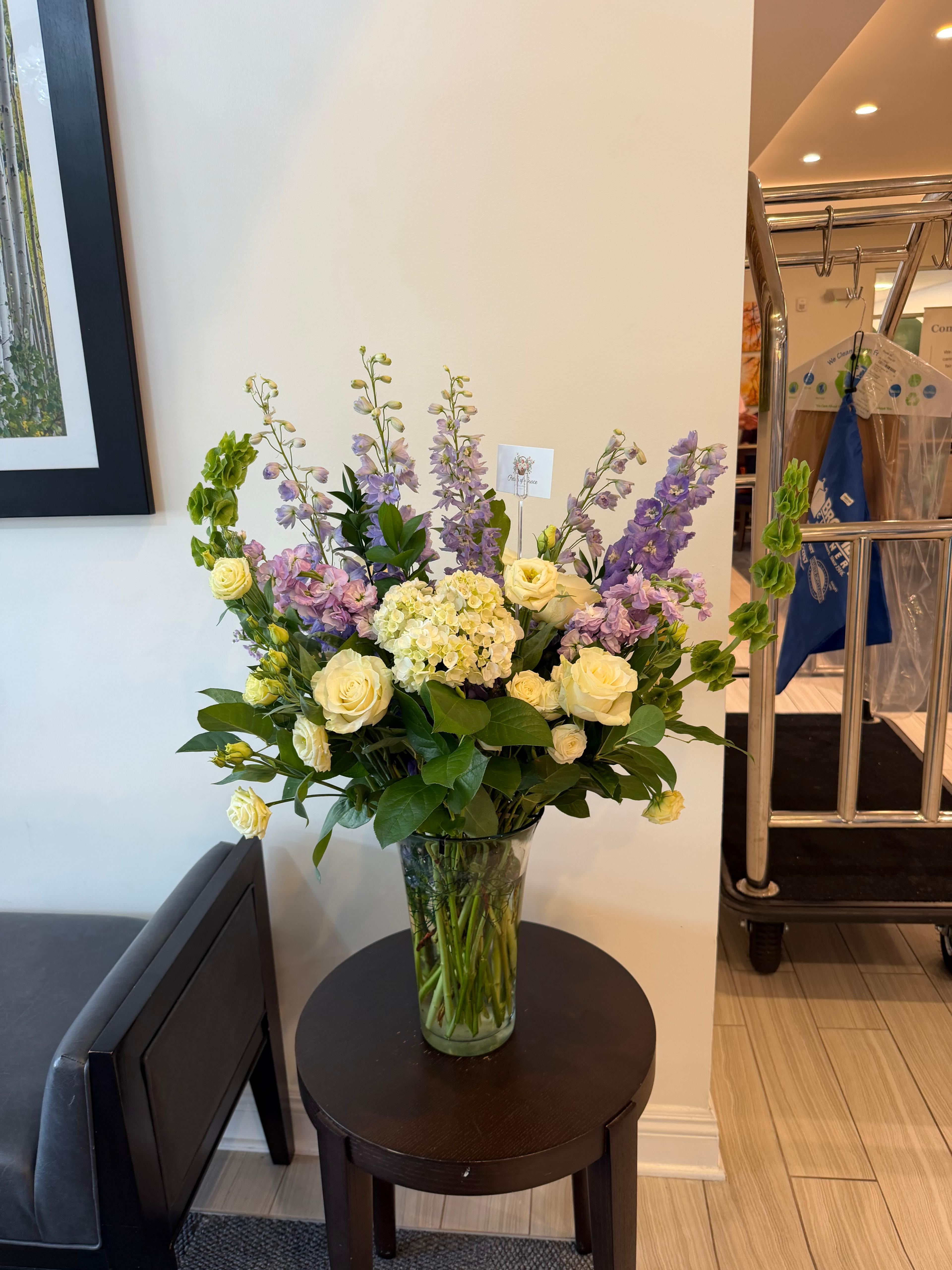 Glass vase filled with white florals with pops of purple