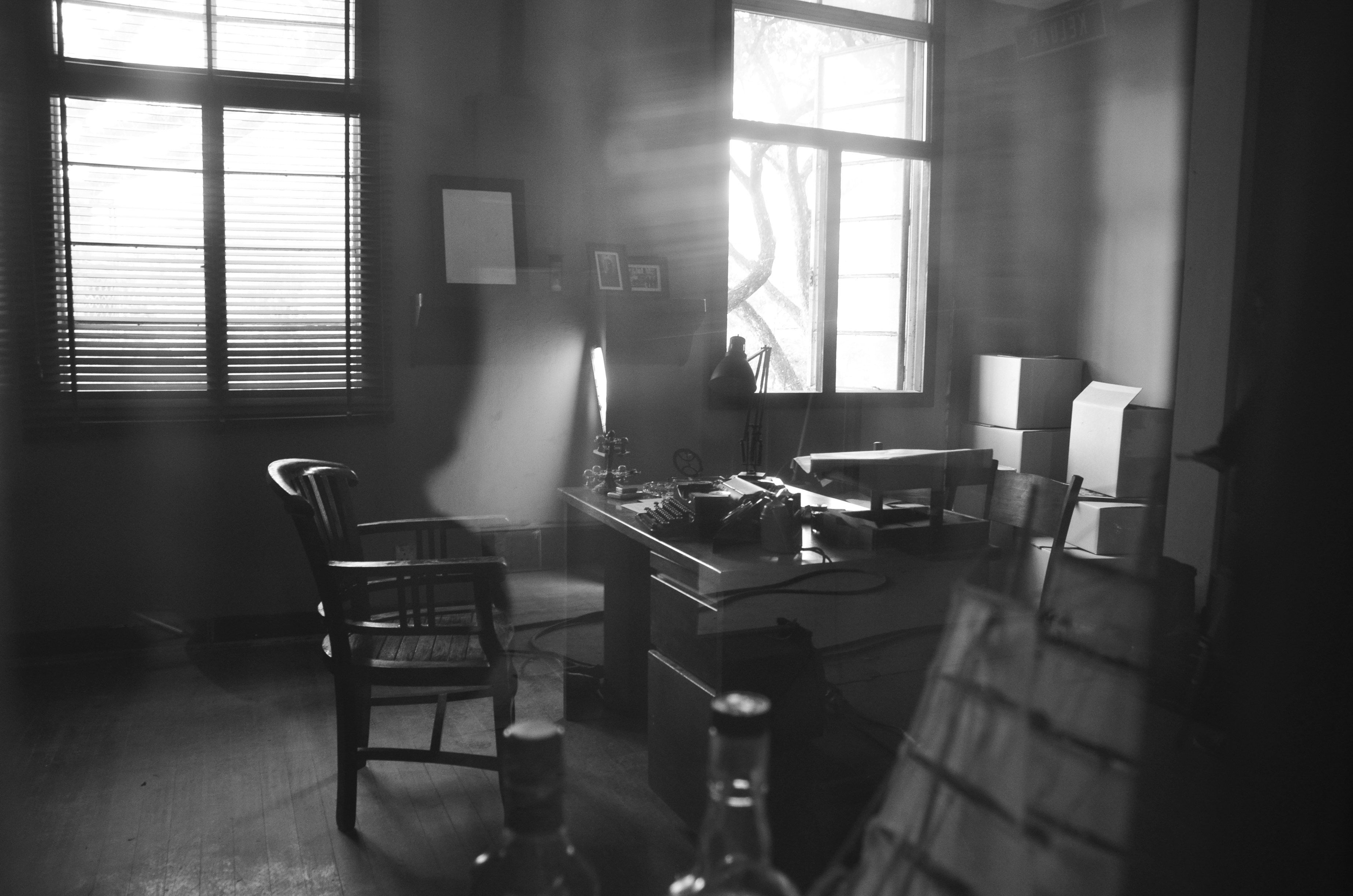 a black and white photo of an office with a desk and chair .