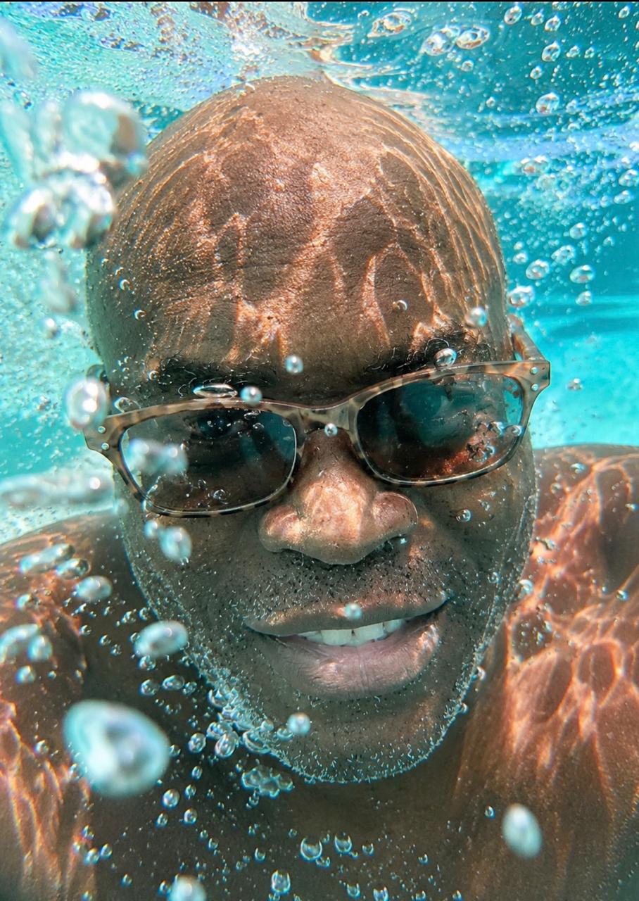 A guest's face close up just under the surface, bubbles rising past him