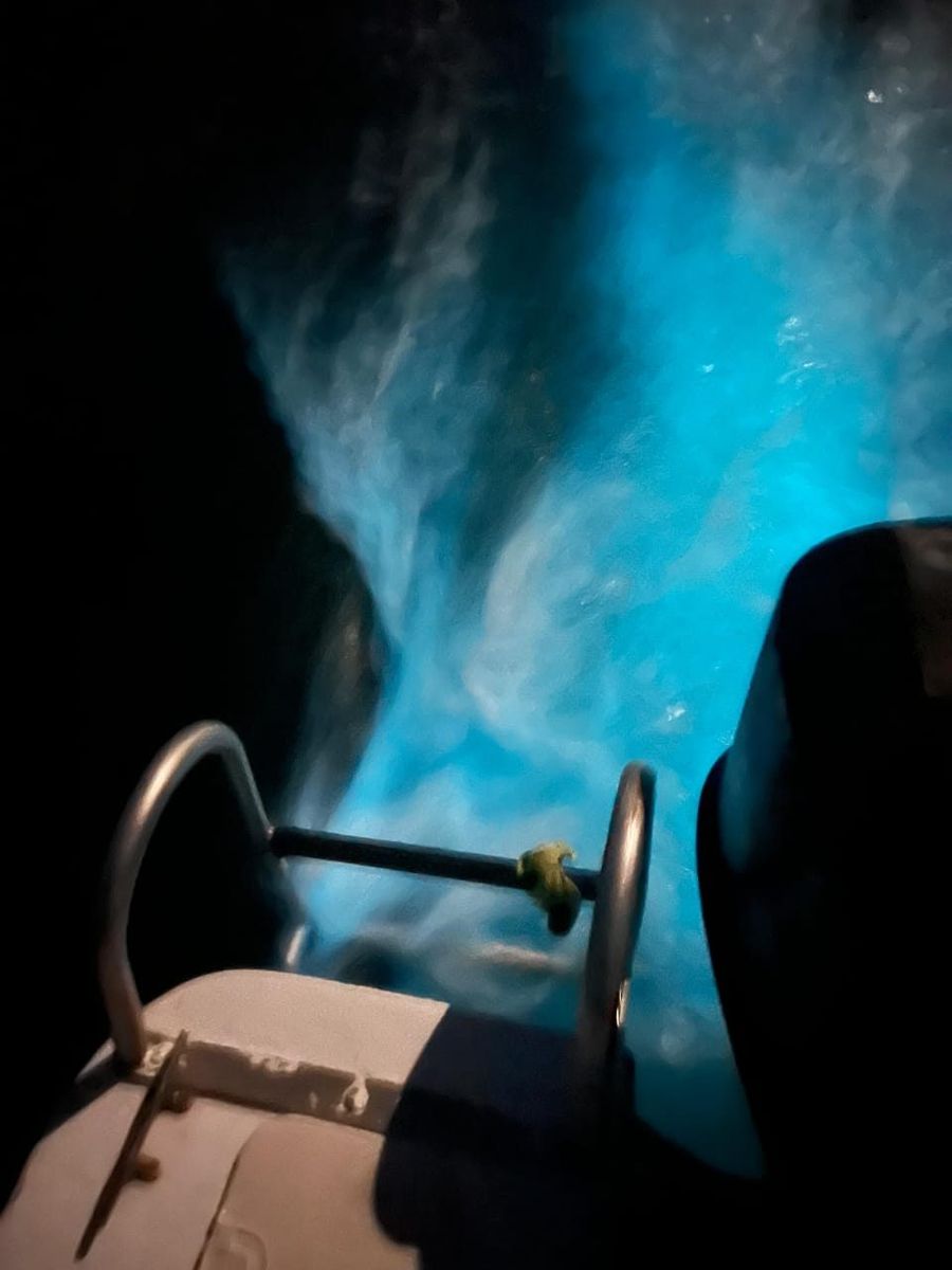 Glowing blue water churning alongside the boat at night