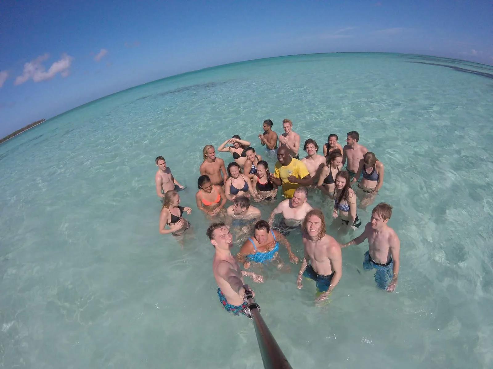 A large group of guests standing together in the shallow clear water of the Nylon Pool