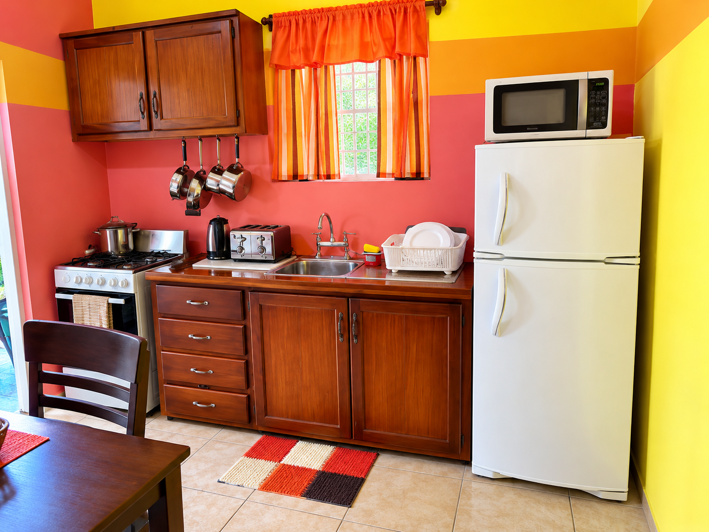 The apartment kitchen with a full cooker, fridge and red cabinetry