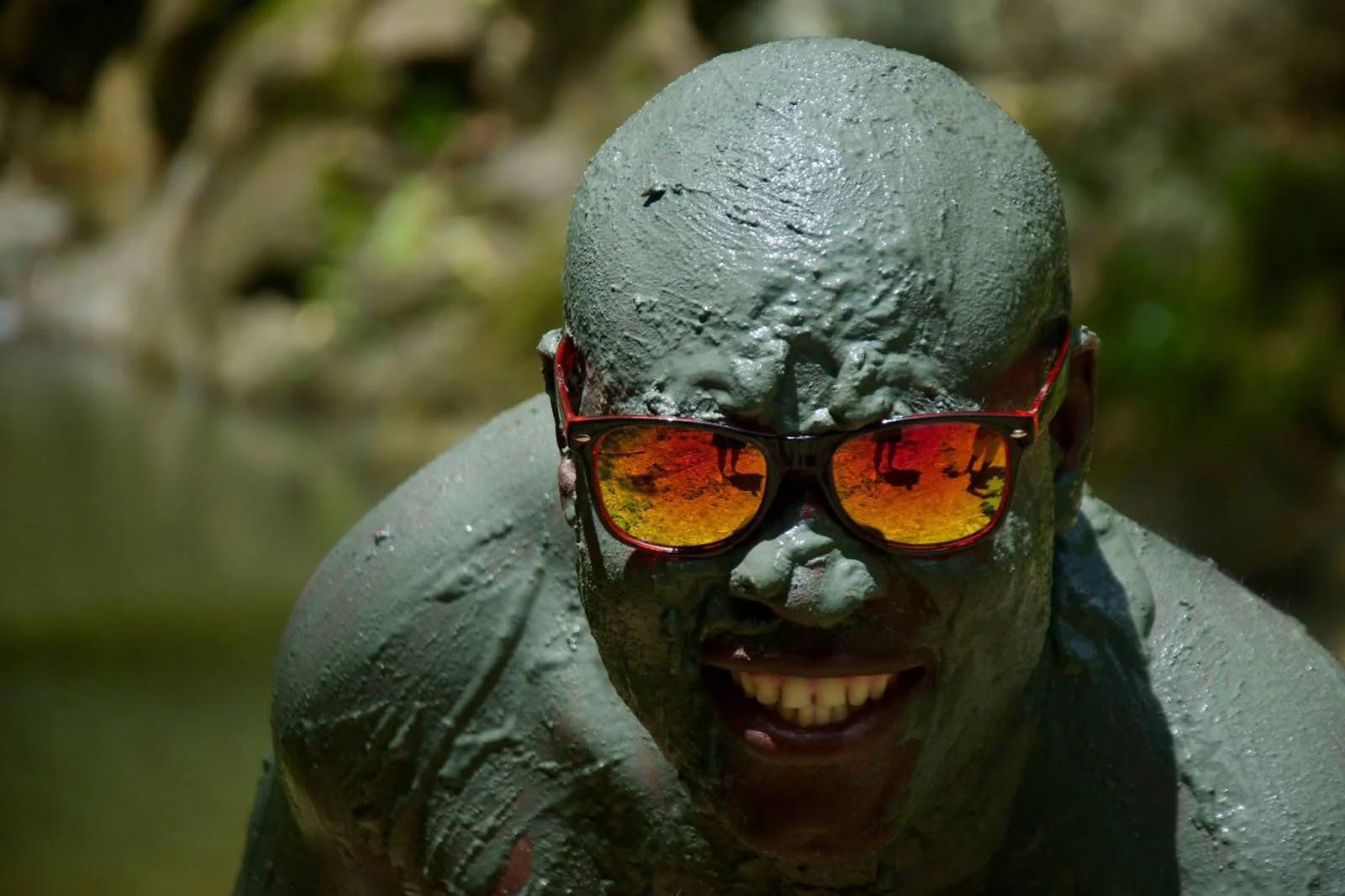 A guest coated head to toe in grey mud at the volcano