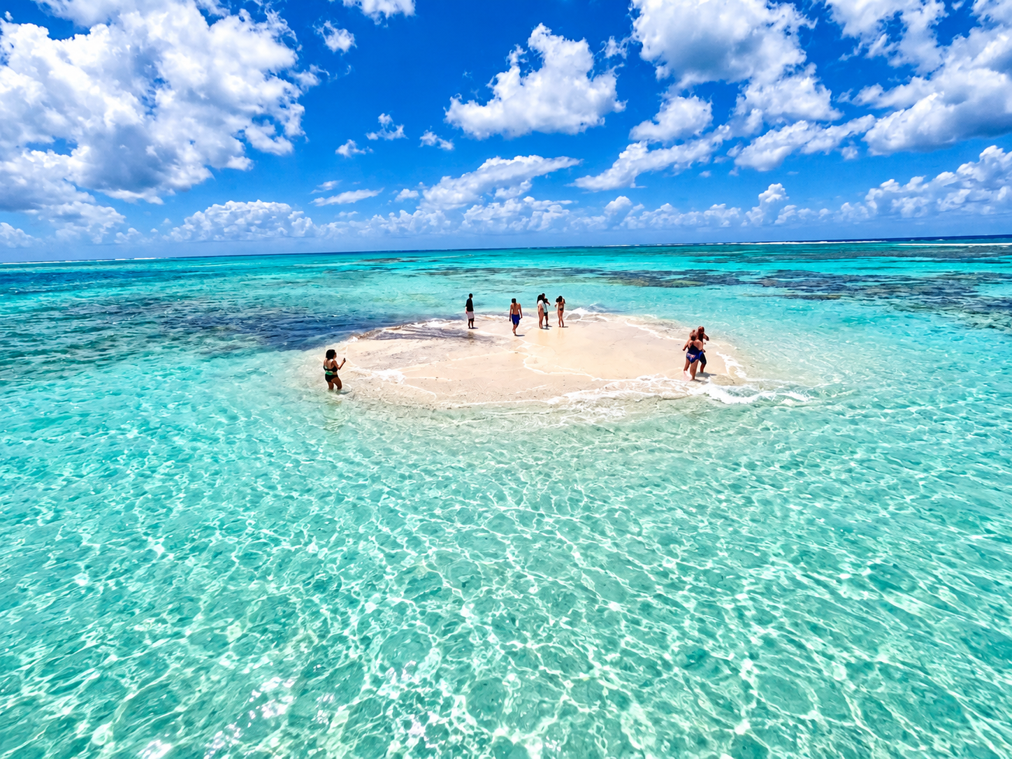 Some guests standing on the Nylon Pool sandbank, waist-deep in clear water in the middle of the sea