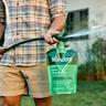 Person spraying Sunday Grass Powerhouse liquid lawn nutrients with a hose end sprayer in a backyard.