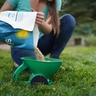 A woman pouring grass seed into a spreader