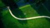 Aerial shot of a lawn with a path winding its way through. A group of people sits in the center of the lawn.