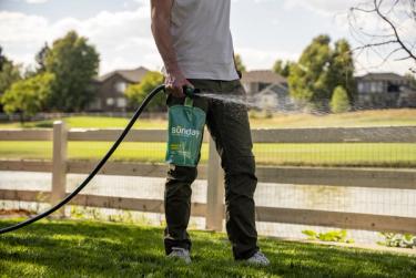 Man applying unused Mighty Green on lawn to use leftover Sunday fertilizer