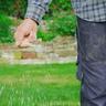 A man hand-spreading grass seed, demonstrating how to plant grass