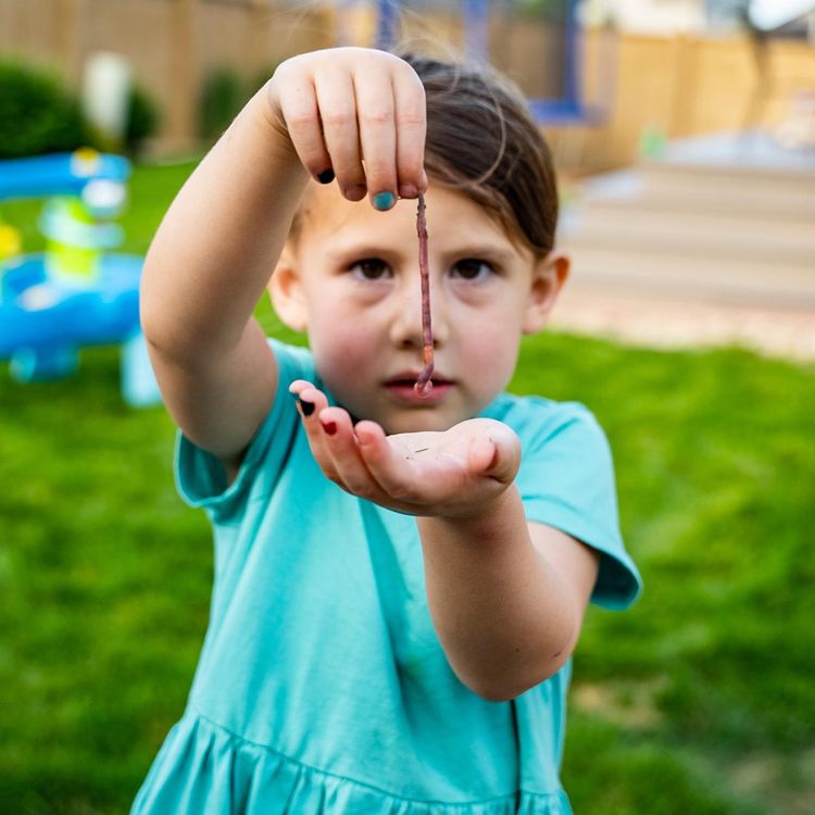 Child holding a worm.