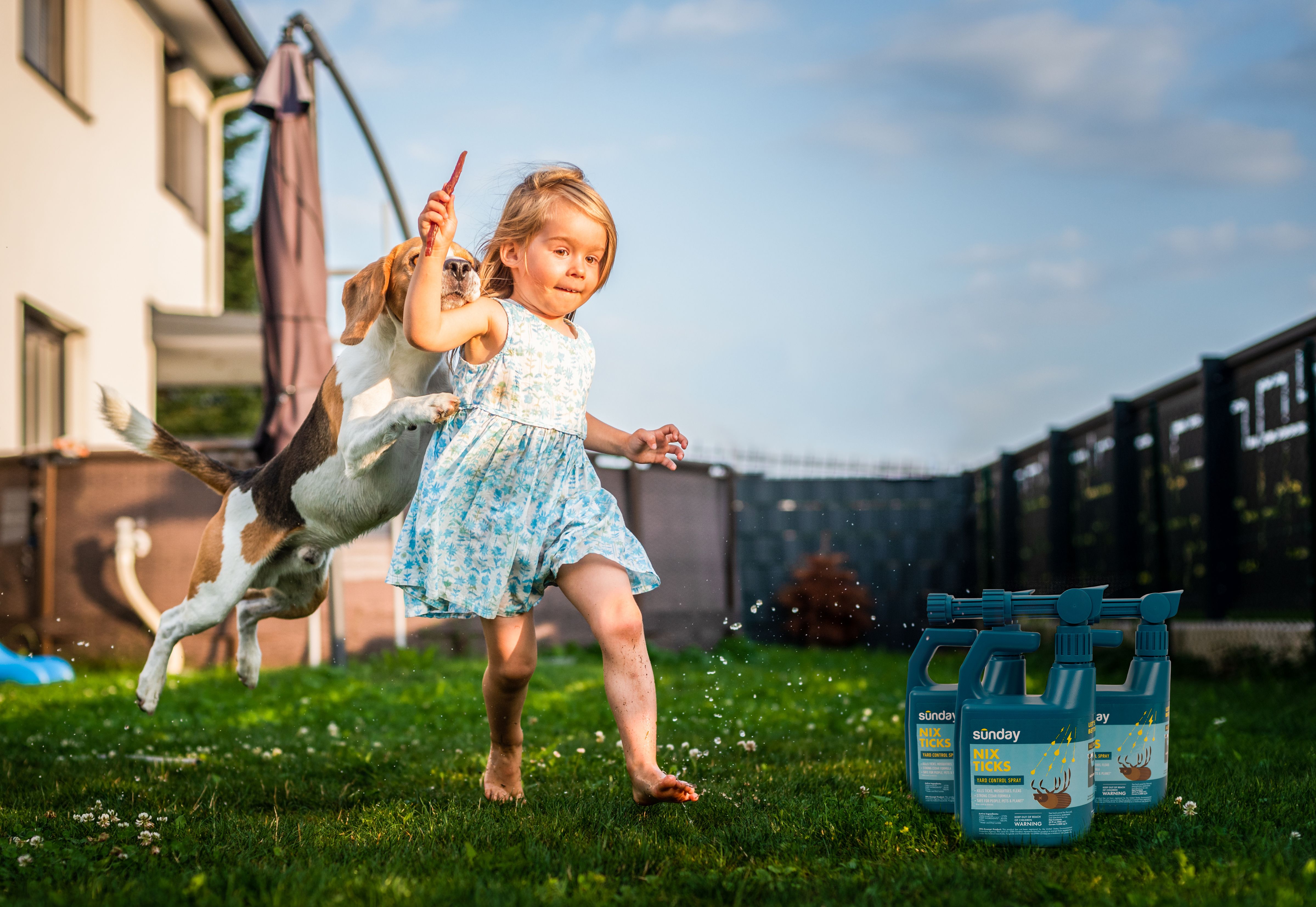 A girl and her dog play on a lawn next to tick control products
