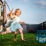 A girl and her dog play on a lawn next to tick control products