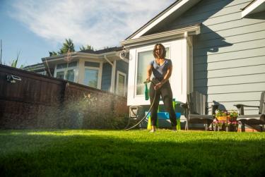 Woman applying Weed & Green across lawn