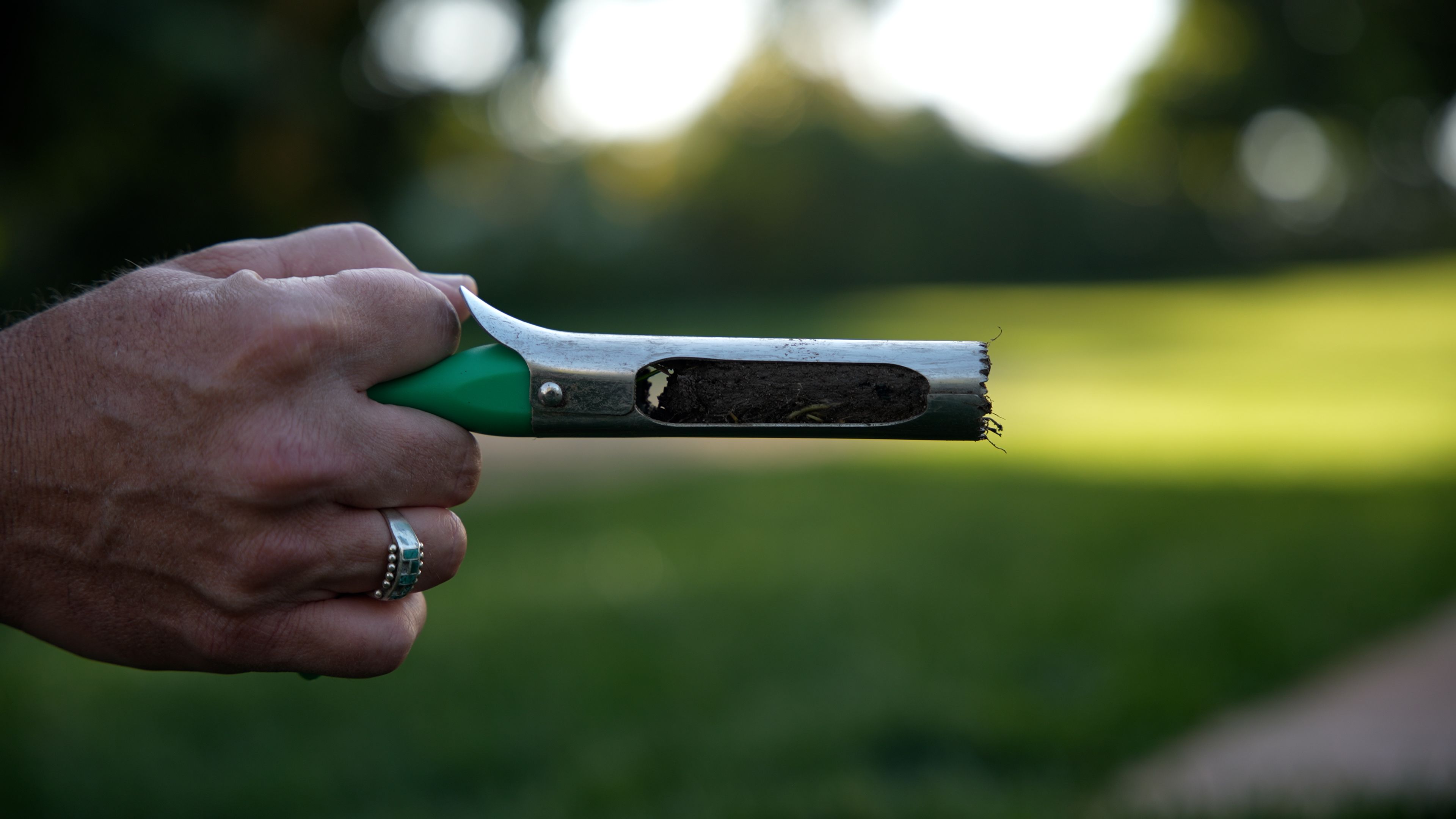 Hand holding soil coring tool filled with soil