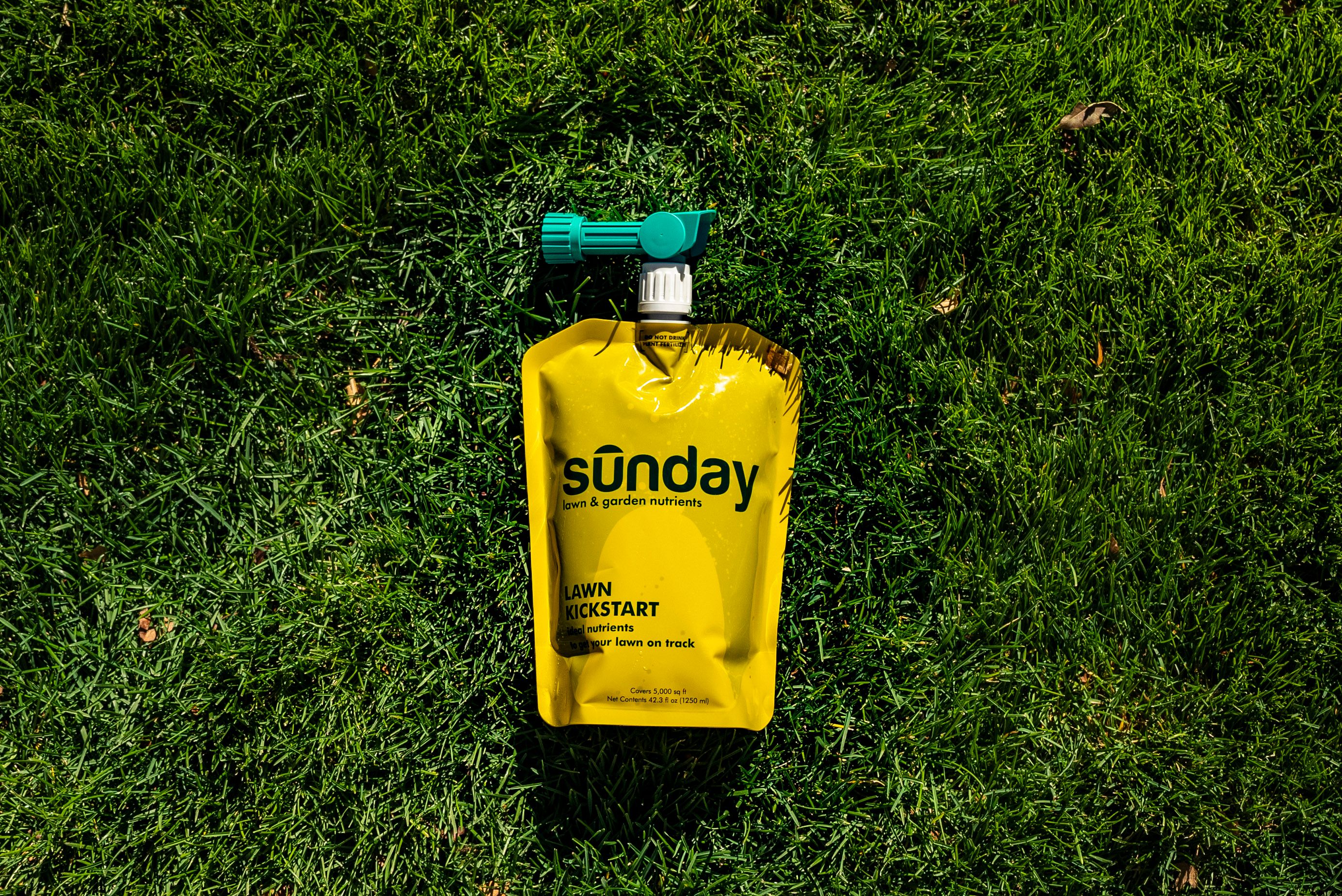 Sunday Lawn Kickstart liquid fertilizer pouch and hose-end sprayer on lawn