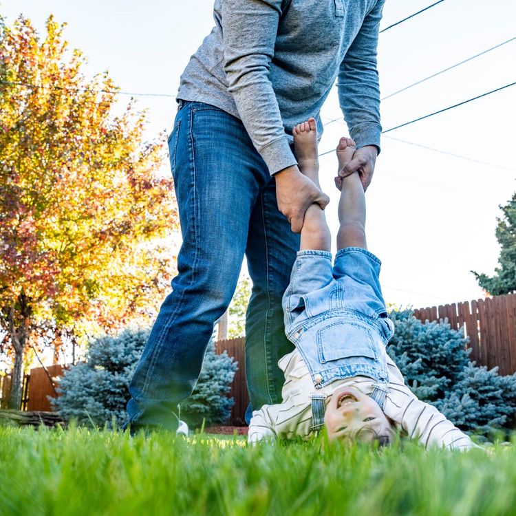 Parent and child playing in green, weed-free grass