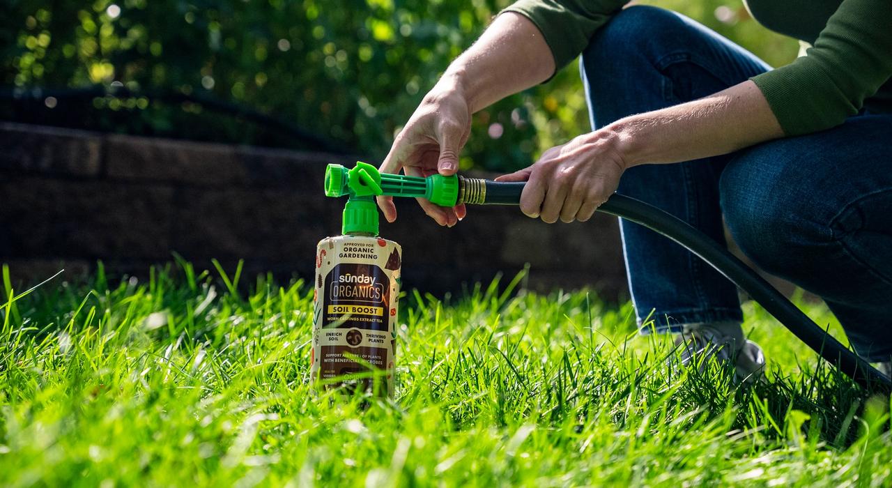 Soil Boost with hose-end attachment in lawn next to garden