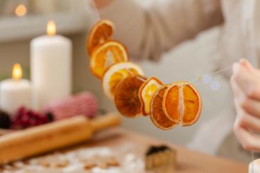 A garland of dried citrus with candles burning in the background.