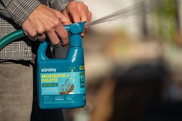 Person spraying Mosquito Deleto outdoors.
